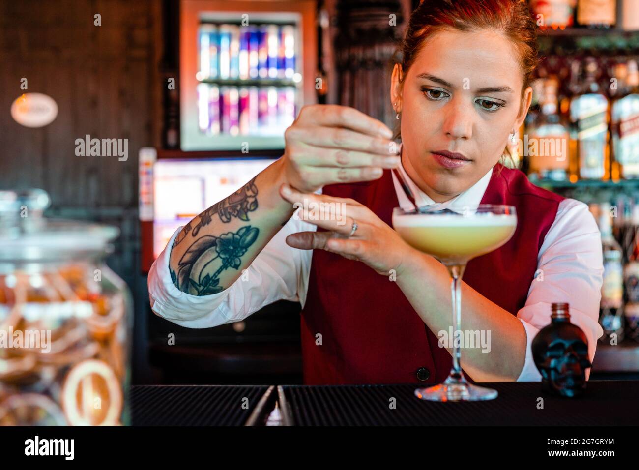Barista professionista giovane femmina che aggiunge alcool dal biberon a  forma di cranio con contagocce in vetro mentre prepara un cocktail acerbo  al bar Foto stock - Alamy
