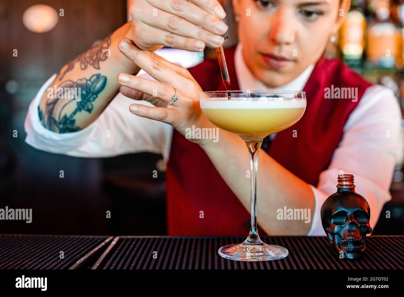 Il barista aggiunge il ghiaccio nel bicchiere da cocktail con la
