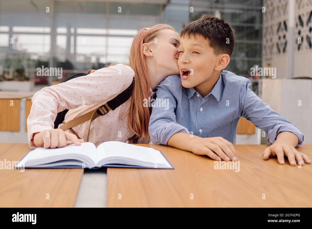 adolescente studentessa sta sussurrando qualcosa nell'orecchio del ragazzo o baciando. Primo amore Foto Stock