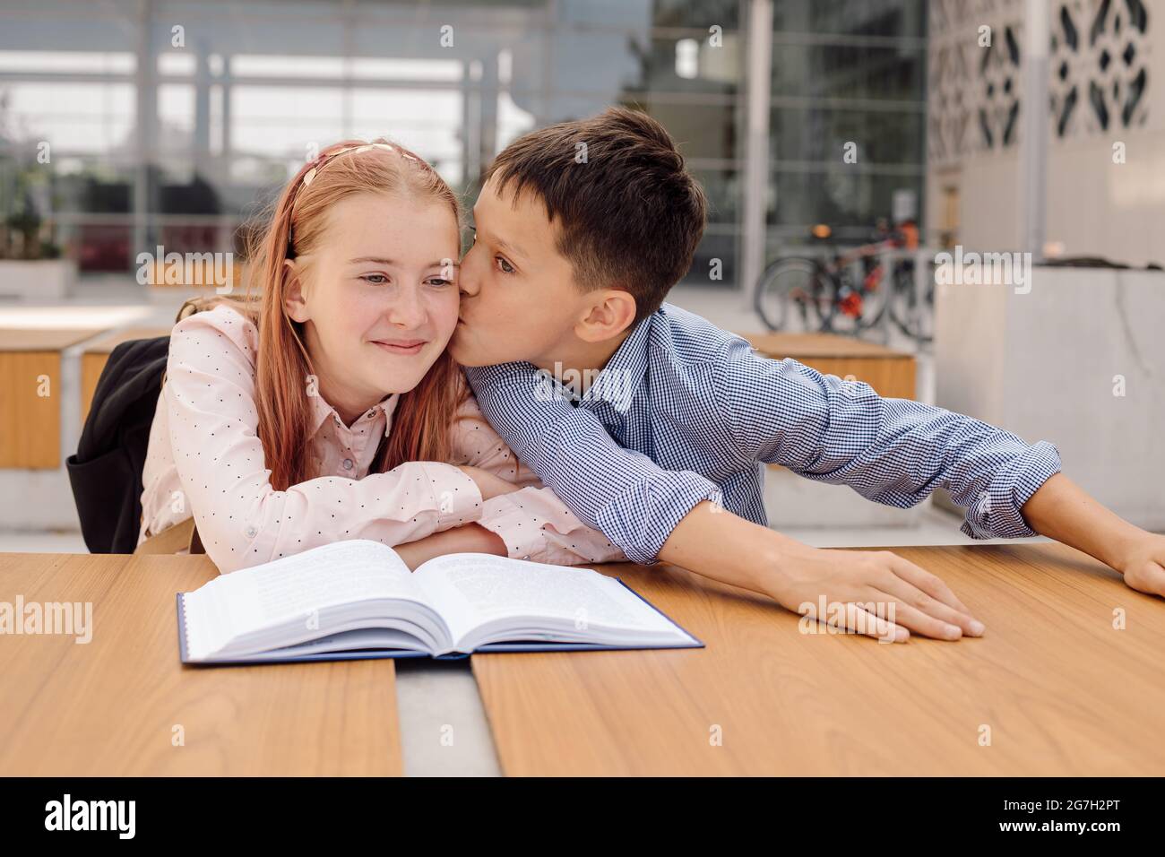il ragazzo bacia la ragazza nel cortile della scuola. concetto di amore della prima scuola Foto Stock