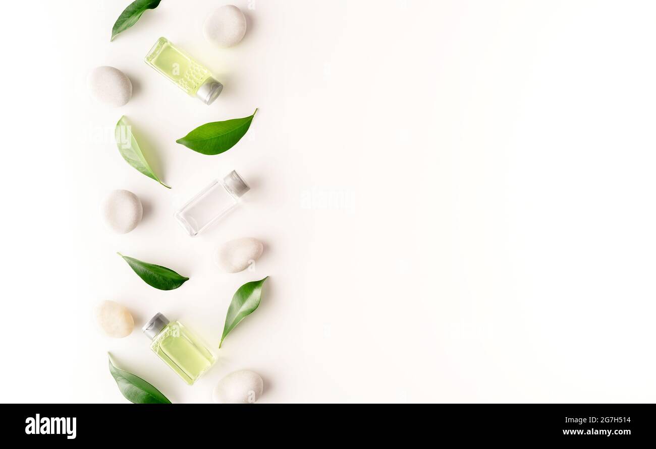 Bella composizione termale di cosmetici naturali con ciottoli di mare e foglie verdi su sfondo bianco. Progettazione di banner cosmetici. Vista dall'alto. Disposizione piatta. COP Foto Stock