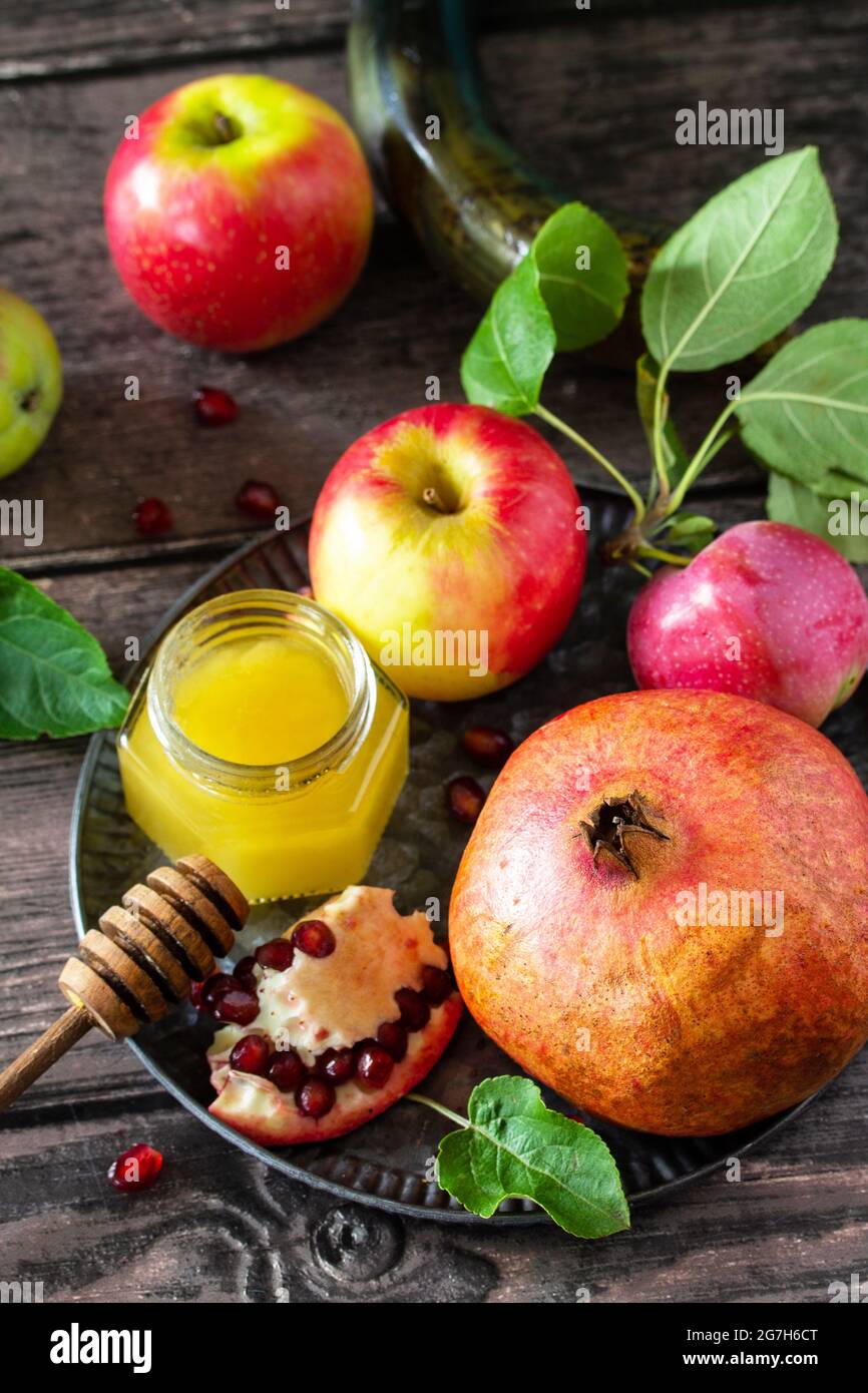 Immagine religiosa del concetto di Rosh hashanah (festa ebraica di Capodanno). Simboli tradizionali: Miele, mele e melograno su un tavolo rustico scuro. Foto Stock