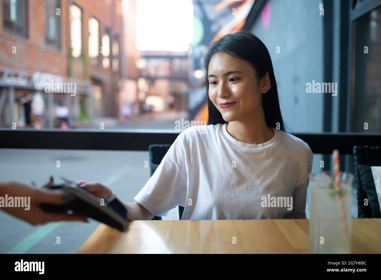 Asian Donna pagare con carta di credito contactless cassa di pagamento in caffetteria all'aperto. Foto Stock