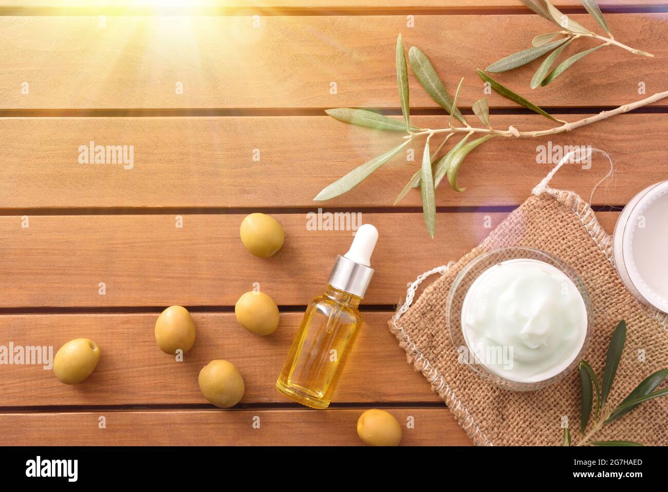 Crema naturale di pelle con estratto di oliva e siero con ramificazione e olive su tavola di legno. Vista dall'alto. Foto Stock