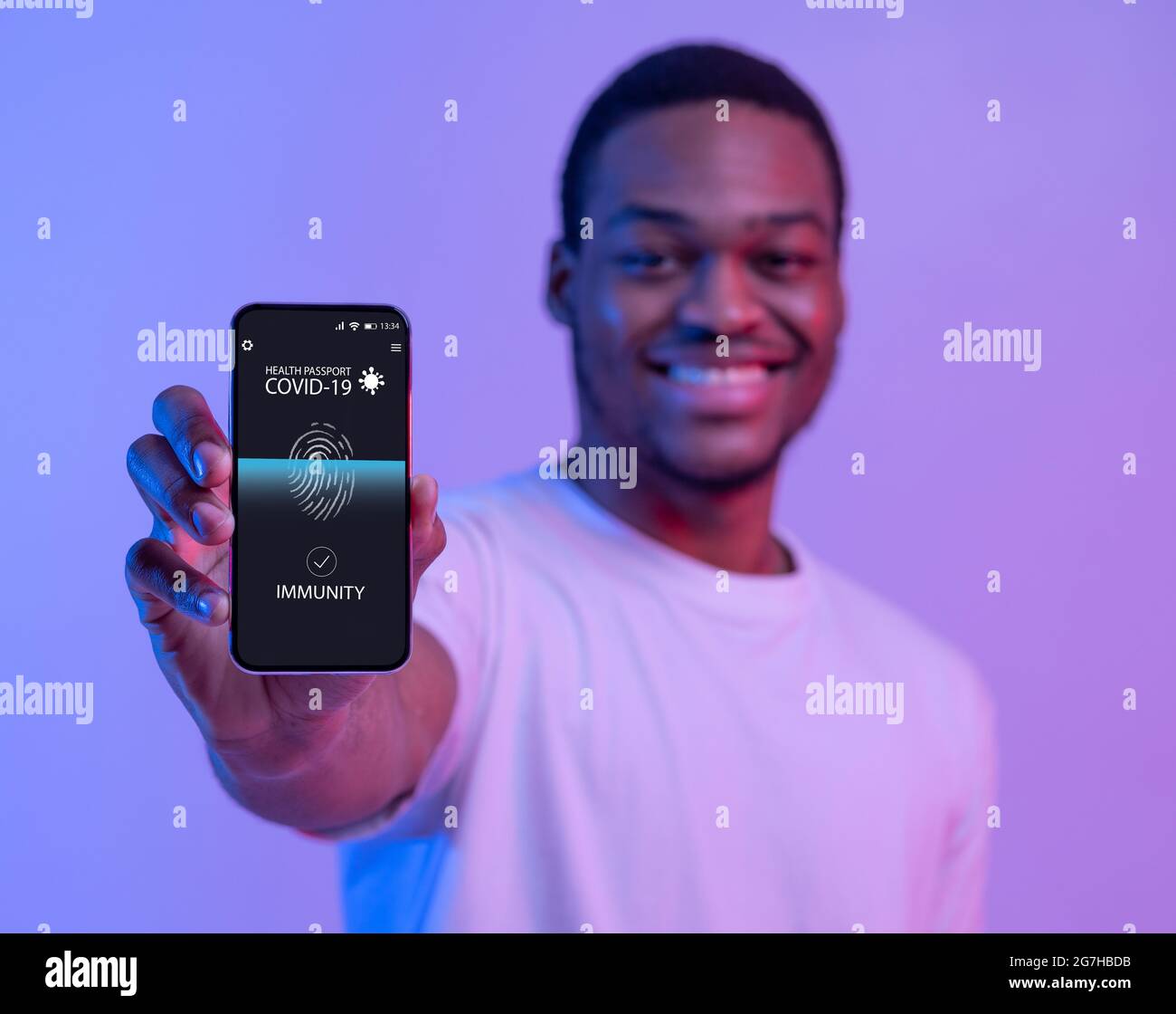 Identificazione biometrica. Ritratto di sorridente uomo nero che tiene cellulare con digitale internazionale salute e-passaporto in mano, mostrando immunità per c Foto Stock
