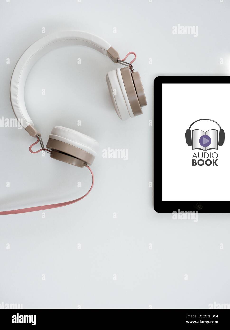 Tablet con icona per audiobook e cuffie su sfondo bianco. Concetto di biblioteca digitale. Scatto in testa. Spazio di copia. Foto Stock