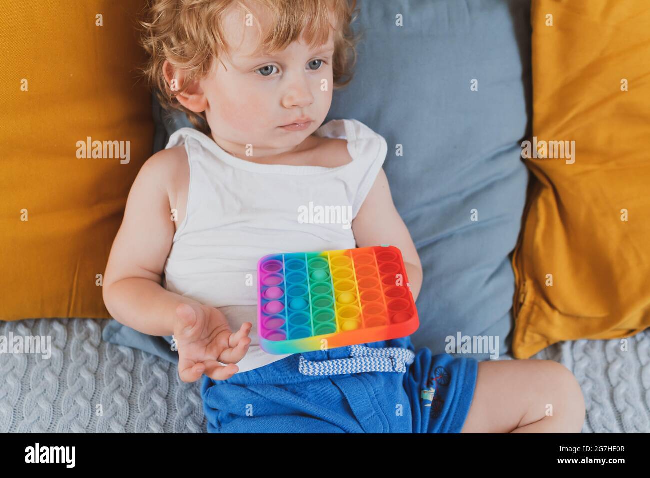 Bambino che tiene i giocattoli sensoriali anti di pop di stress esso nella sua mano giovane toddler che si intreccia con il giocattolo sensoriale di fidget Foto Stock