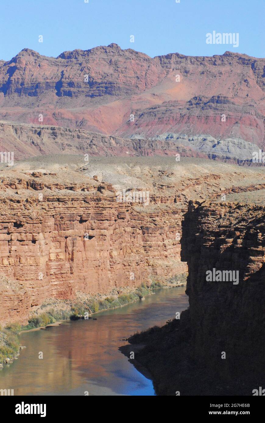 Il paesaggio verticale splendidamente colorato del terreno riflette il fiume Colorado dell'Arizona, con montagne e mesas sullo sfondo. Foto Stock