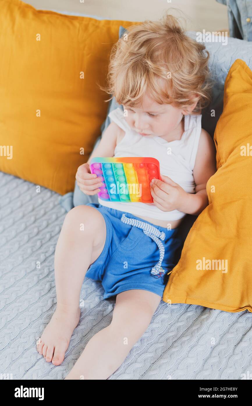 Bambino che tiene i giocattoli sensoriali anti di pop di stress esso nella sua mano giovane toddler che si intreccia con il giocattolo sensoriale di fidget Foto Stock