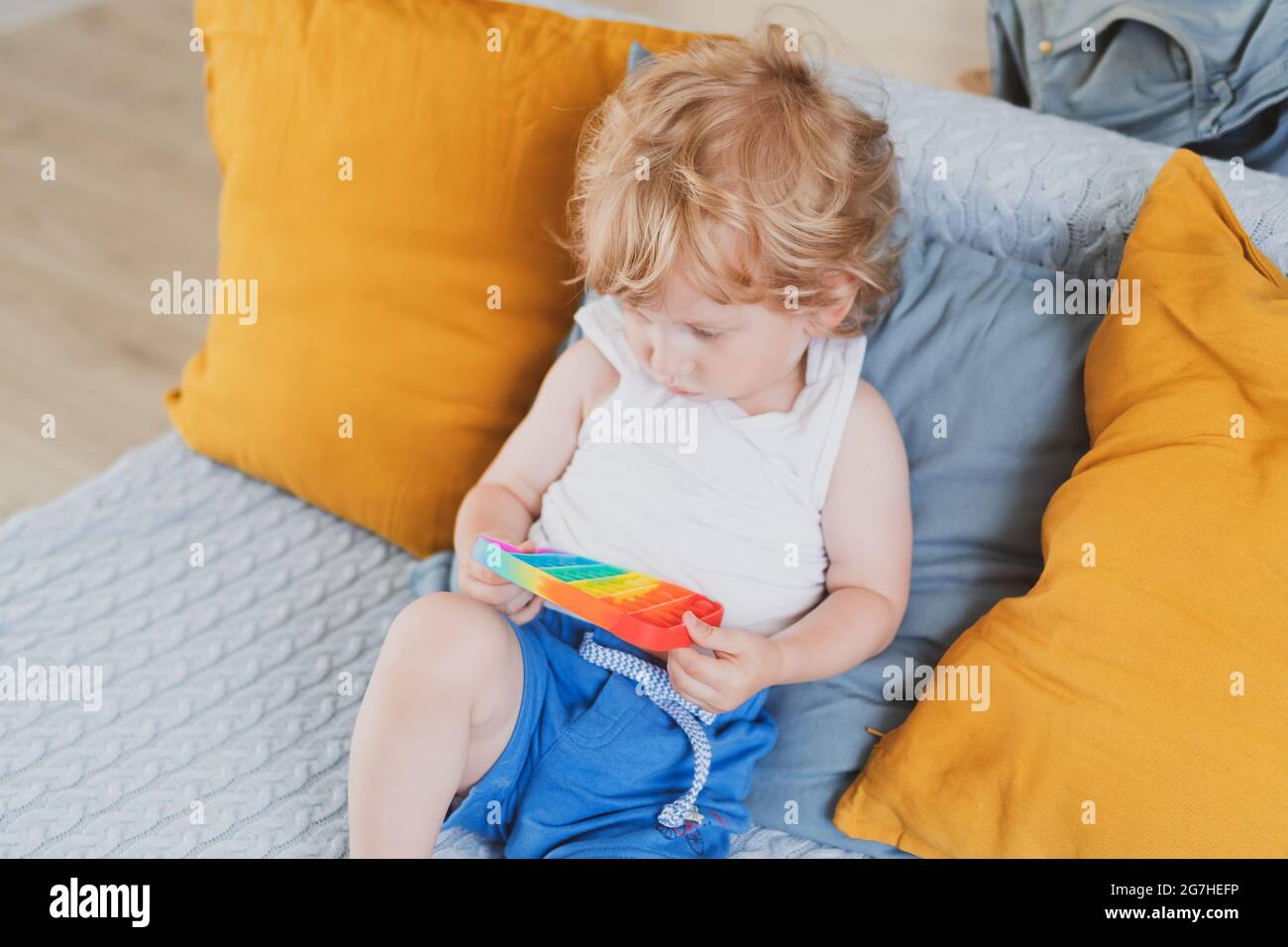 Bambino che tiene i giocattoli sensoriali anti di pop di stress esso nella sua mano giovane toddler che si intreccia con il giocattolo sensoriale di fidget Foto Stock