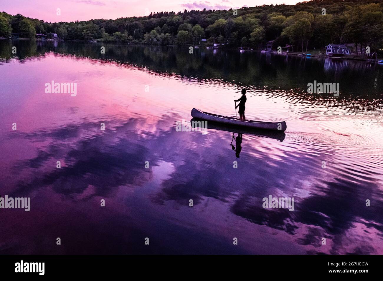 Il canoista si alza in canoa mentre si addica su un piccolo lago vicino a Cooperstown, NY, al tramonto. Foto Stock
