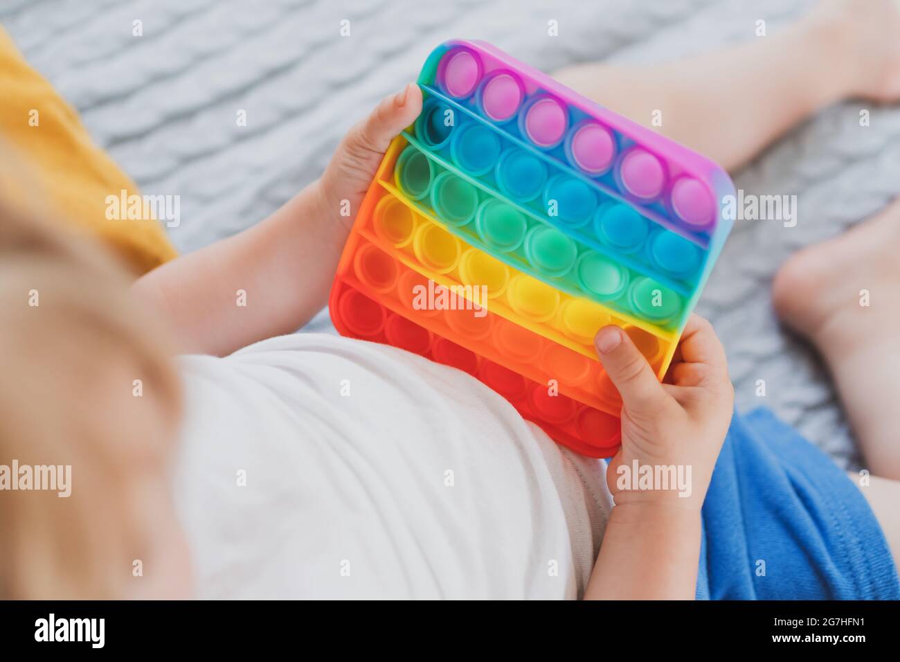 Bambino che tiene i giocattoli sensoriali anti di pop di stress esso nella sua mano giovane toddler che si intreccia con il giocattolo sensoriale di fidget Foto Stock