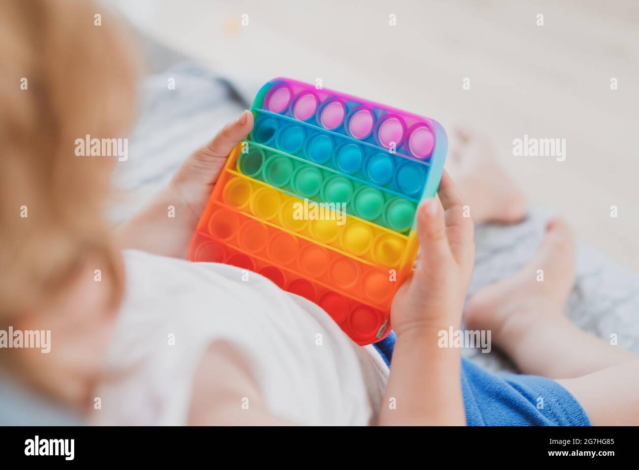 Bambino che tiene i giocattoli sensoriali anti di pop di stress esso nella sua mano giovane toddler che si intreccia con il giocattolo sensoriale di fidget Foto Stock