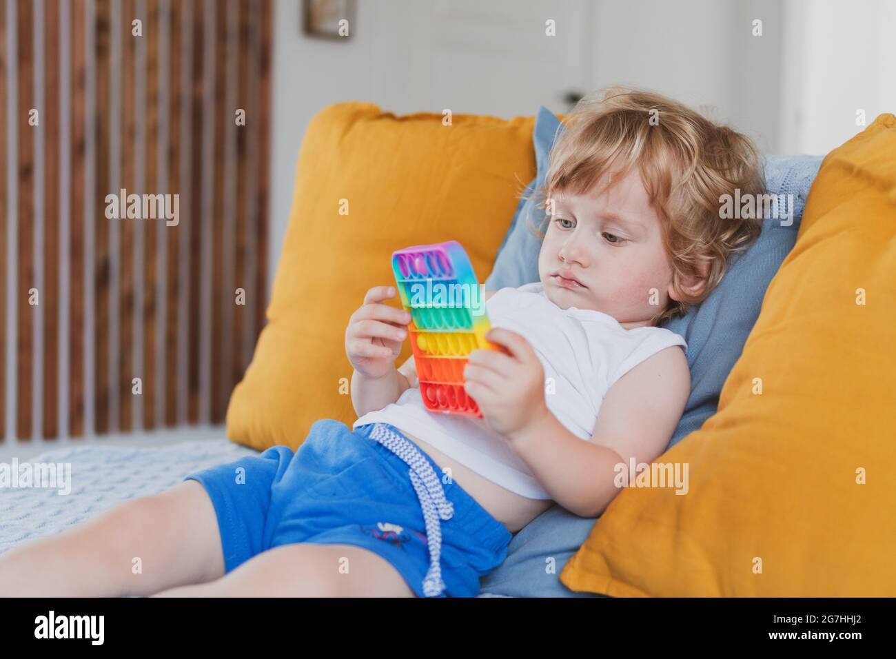 Bambino che tiene i giocattoli sensoriali anti di pop di stress esso nella sua mano giovane toddler che si intreccia con il giocattolo sensoriale di fidget Foto Stock