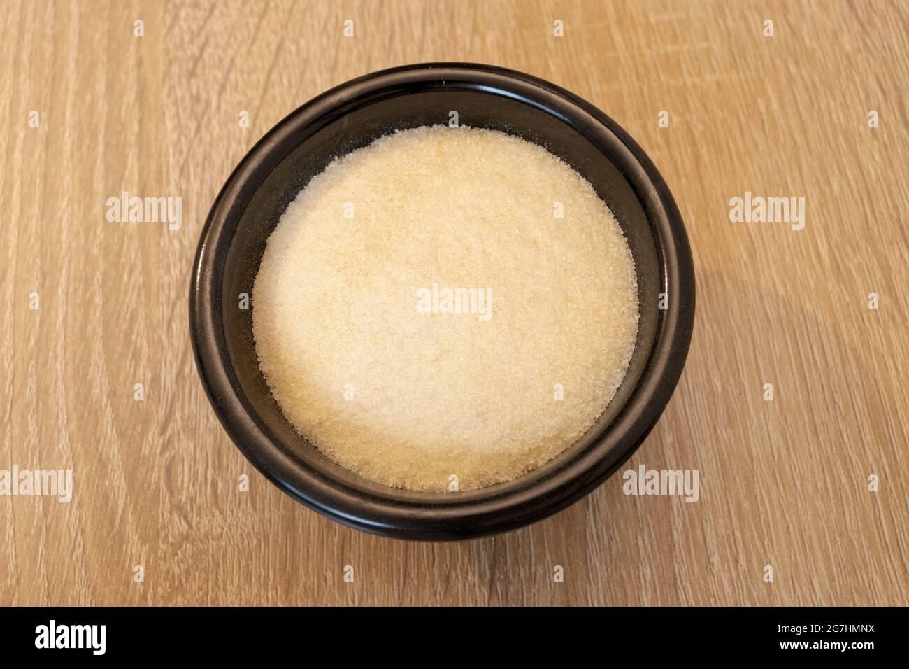 Polvere di gelatina su un recipiente nero. Gelatina in polvere. Grenetina. Foto Stock