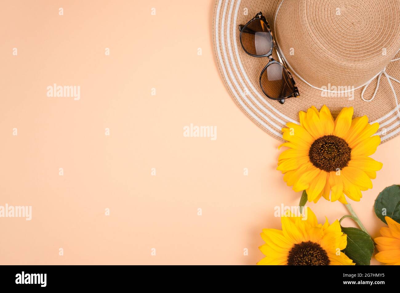 Flatlay con occhiali da sole, cappello di paglia e girasole giallo brillante su sfondo giallo. Foto Stock