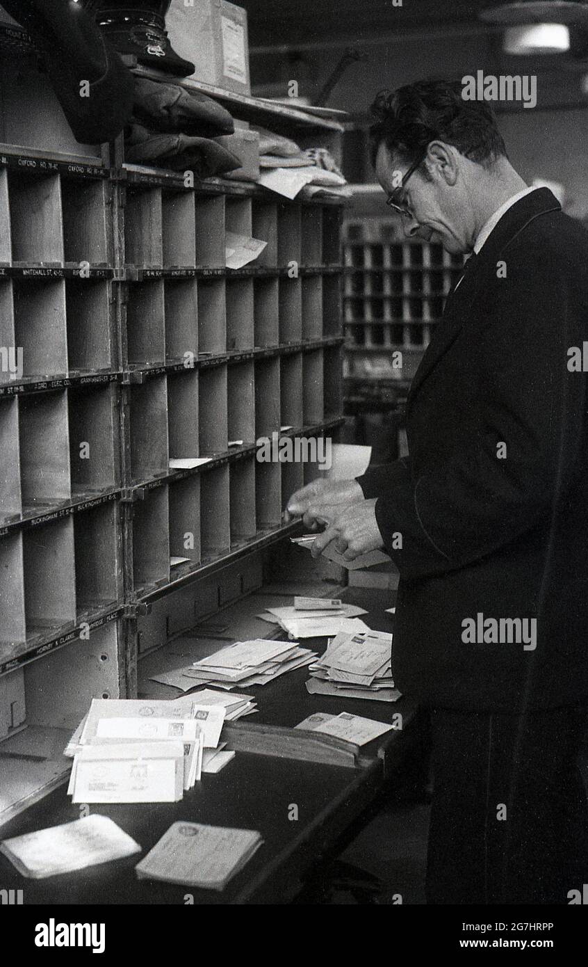 Anni '50, storico, un uomo GPO lavoratore di smistamento di lettere o posta in buca per le strade del distretto, Londra, Inghilterra, Regno Unito. Foto Stock