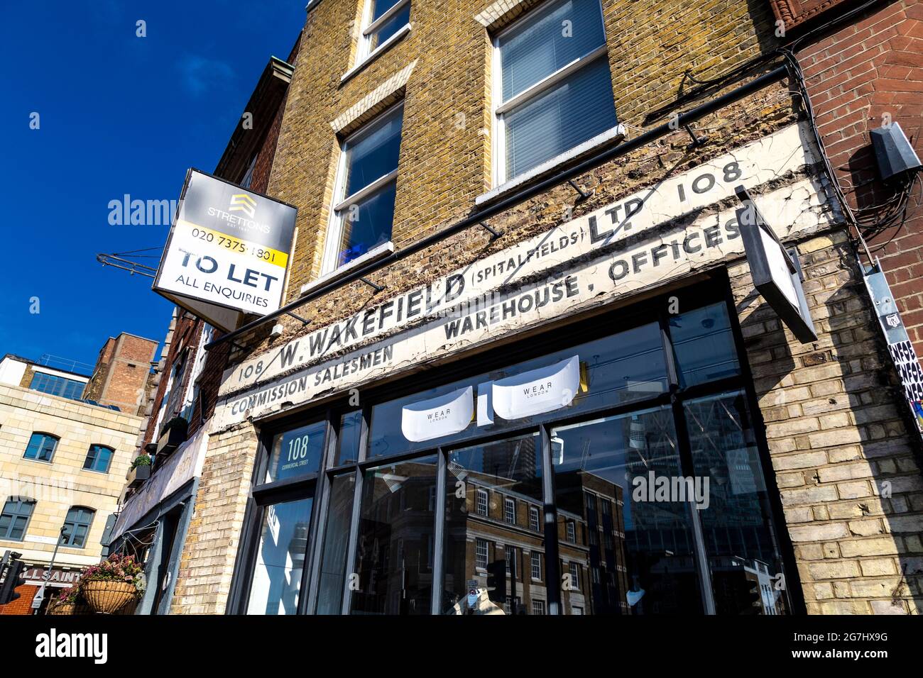Un vecchio cartello per W Wakefield Spitalfields su una facciata, Commercial Street, Spitalfields, Londra, Regno Unito Foto Stock