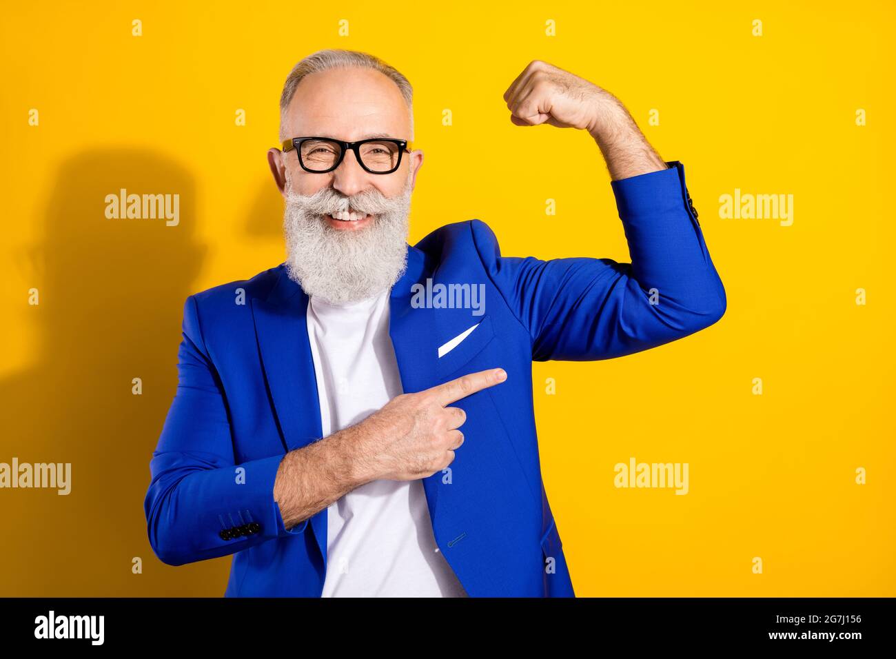 Ritratto di attraente imponente uomo allegro che dimostra muscoli isolati su sfondo di colore giallo brillante Foto Stock