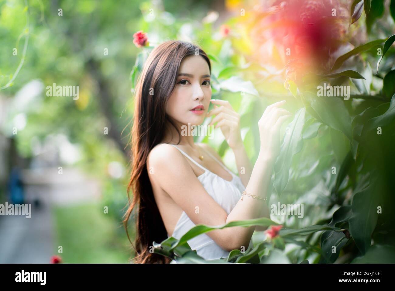 Una bella ragazza da sola in giardino con vestito bianco Foto Stock