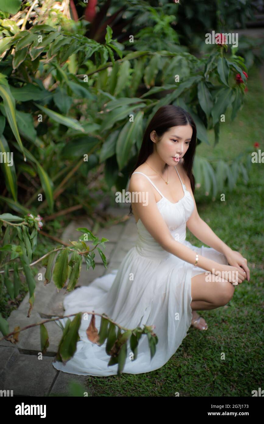 Una bella ragazza da sola in giardino con vestito bianco Foto Stock