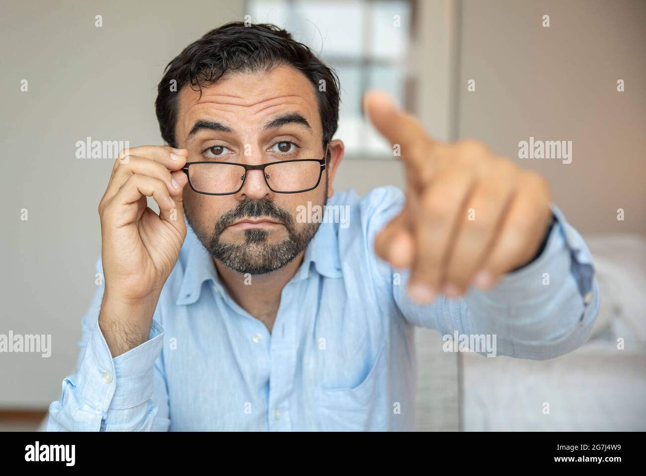 Uomo con una vista povera cercando di regolare i suoi occhiali per vedere meglio Foto Stock