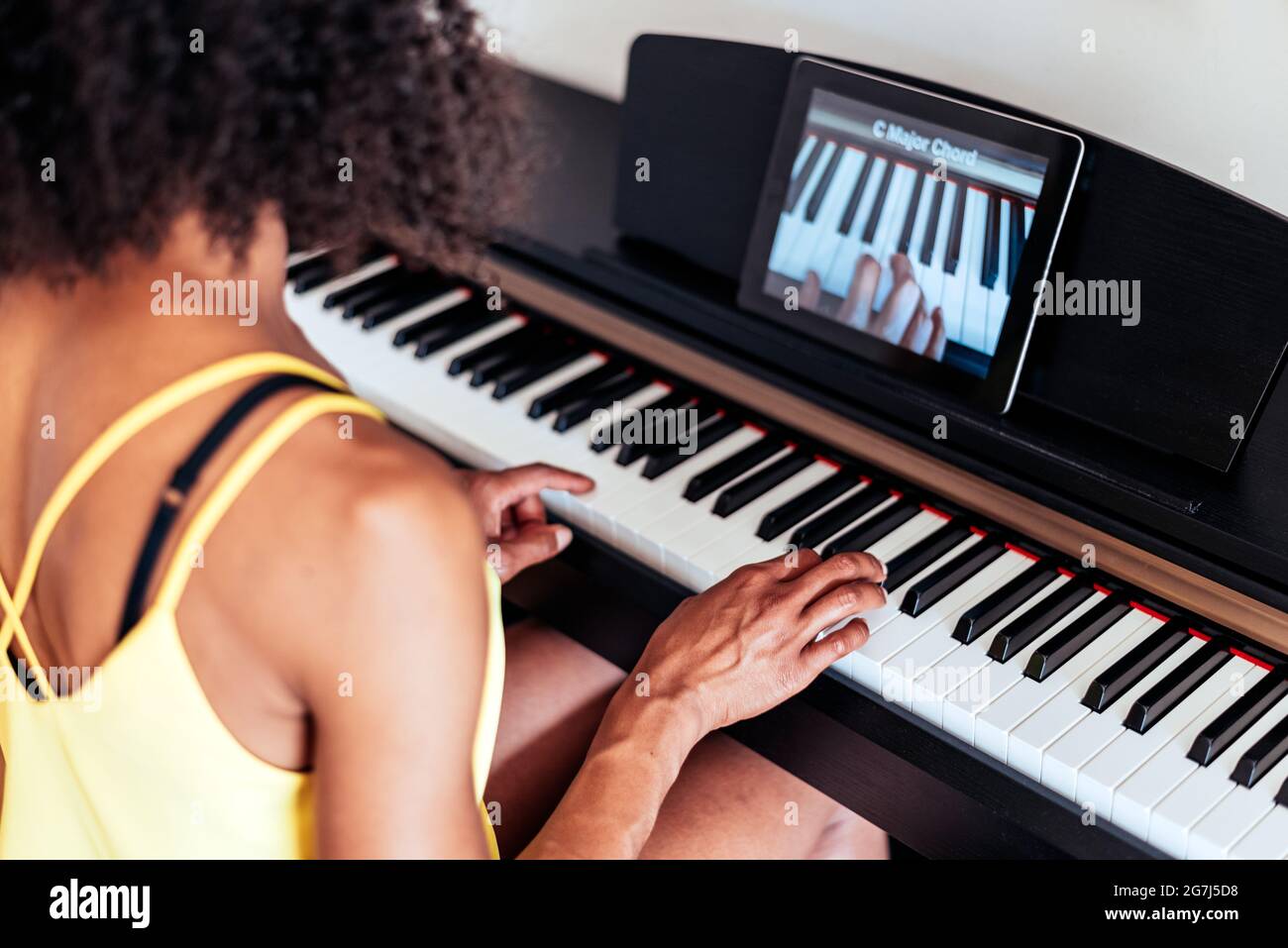 irriconoscibile donna afro americana imparando a suonare il pianoforte con lezioni video. Concetto di apprendimento virtuale. Messa a fuoco selettiva a portata di mano Foto Stock