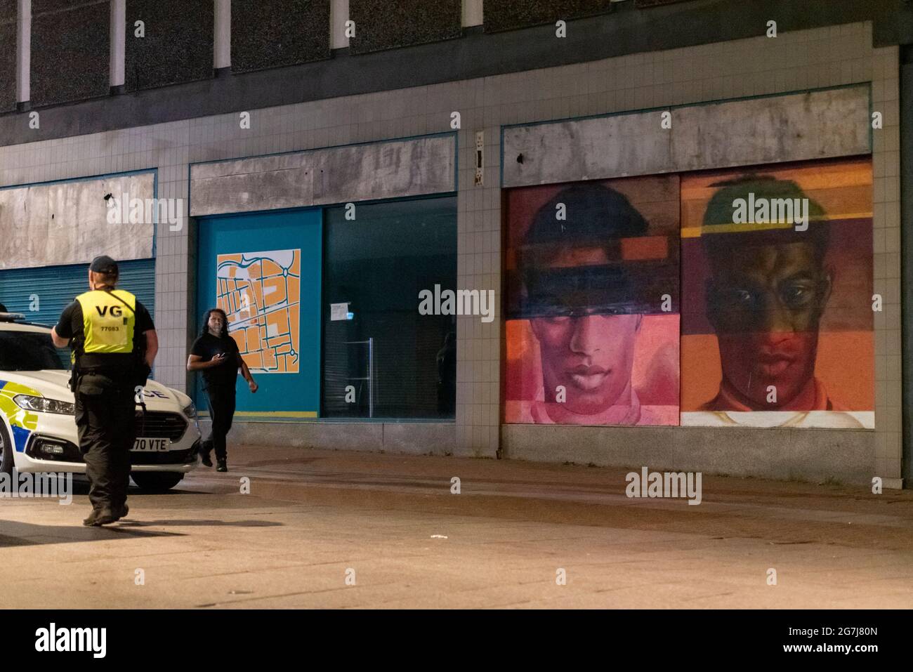 Poliziotto che fornisce sicurezza in High Street a Southend sul Mare, Regno Unito, dopo la sconfitta calcistica in Inghilterra in Italia con il murale Marcus Rashford Foto Stock