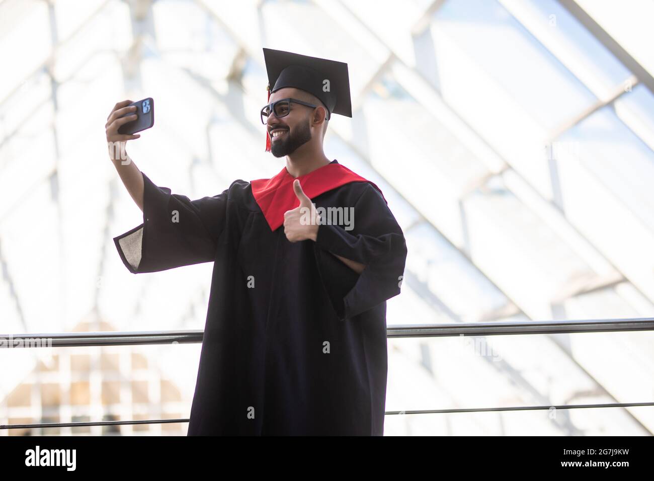 Allegro giovane uomo che indossa il vestito di laurea e che tiene il suo  certificato, prendendo un selfie Foto stock - Alamy