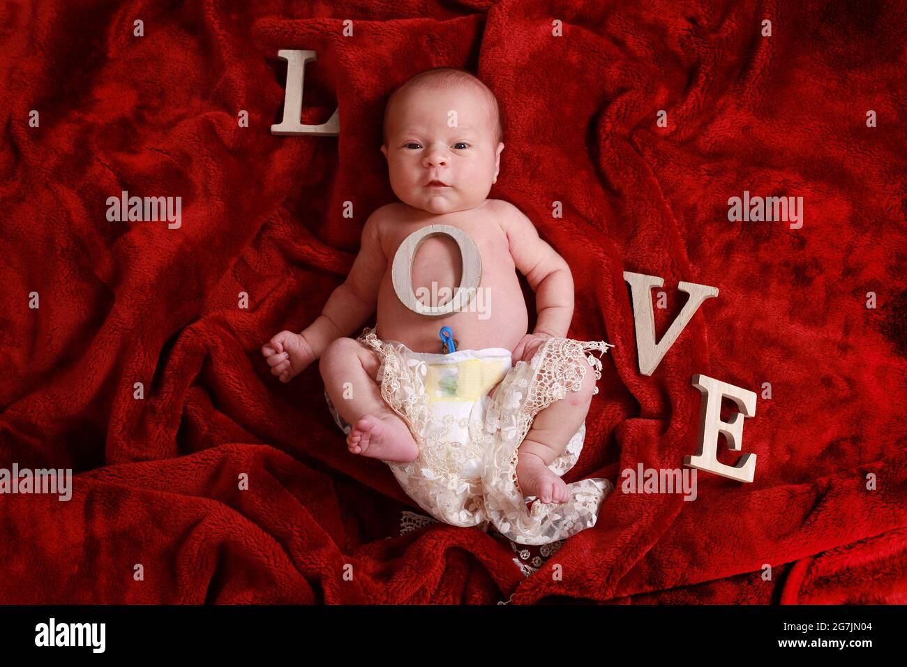 Bambino neonato conCinturno ombelicale ancora attaccato su coperta rossa nella cameretta Foto Stock