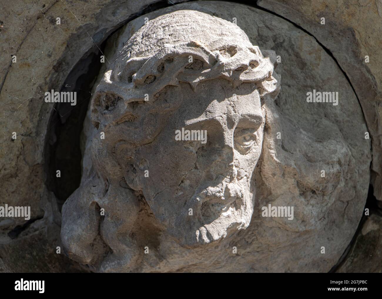 Statua danneggiata di Gesù Cristo su una lapide. Foto Stock