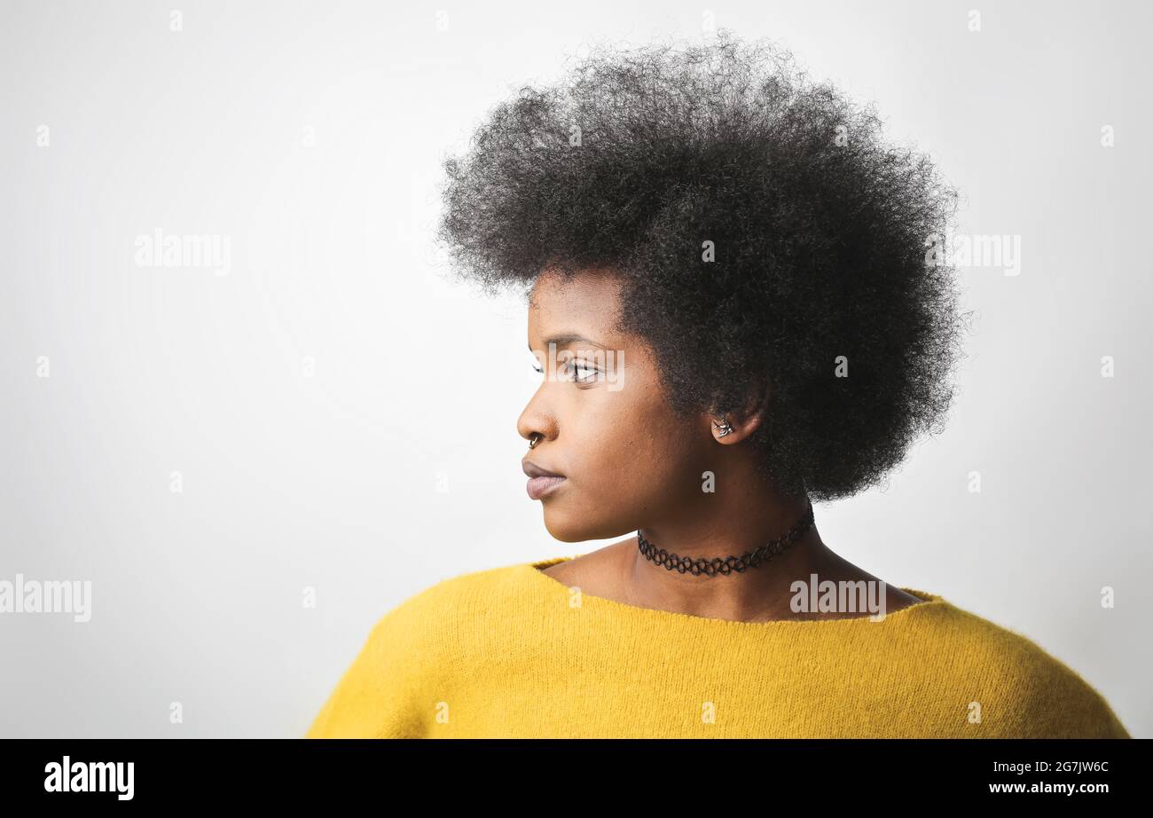 Profilo laterale di una giovane donna nera con capelli ricci corti e maglione giallo Foto Stock