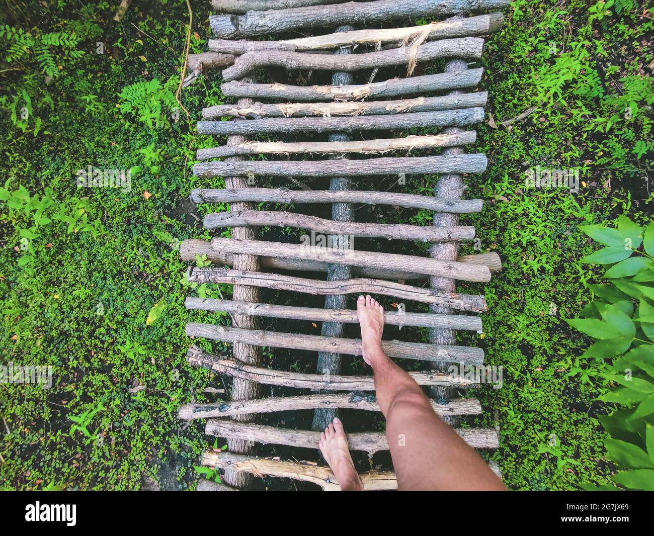 camminando su un piccolo ponte di legno per la natura a piedi. Una passerella in legno conduce attraverso la foresta. Passerella in legno Foto Stock