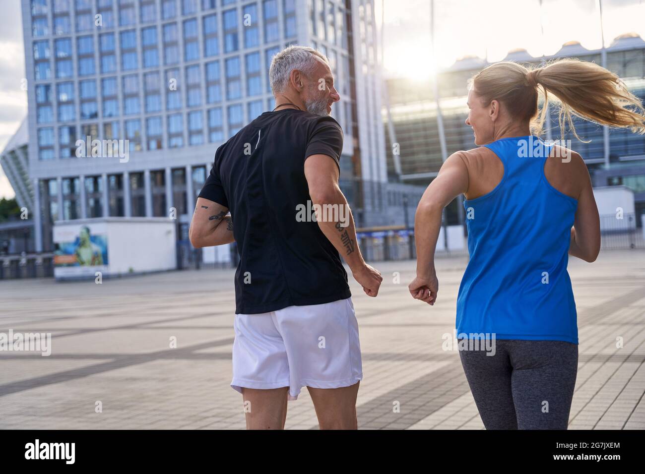 Vista posteriore della coppia di mezza età in abbigliamento sportivo rimanere attivi, jogging insieme in ambiente urbano Foto Stock