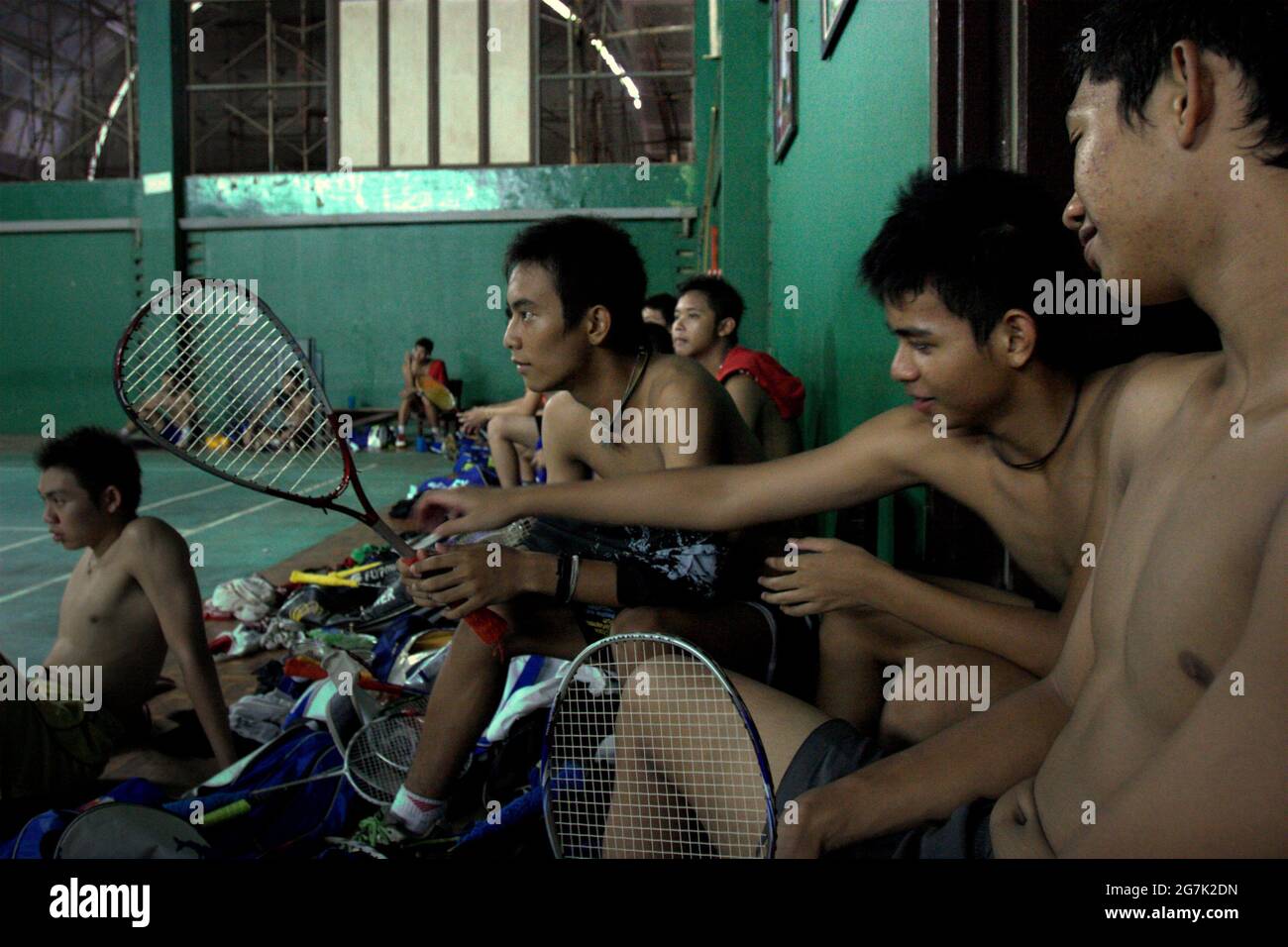 I giovani atleti di badminton riposano dopo una sessione di allenamento, mentre uno di loro sta tenendo una racchetta da tennis usata per il badminton ombra, al Jaya Raya badminton club di Giacarta, Indonesia. Foto Stock