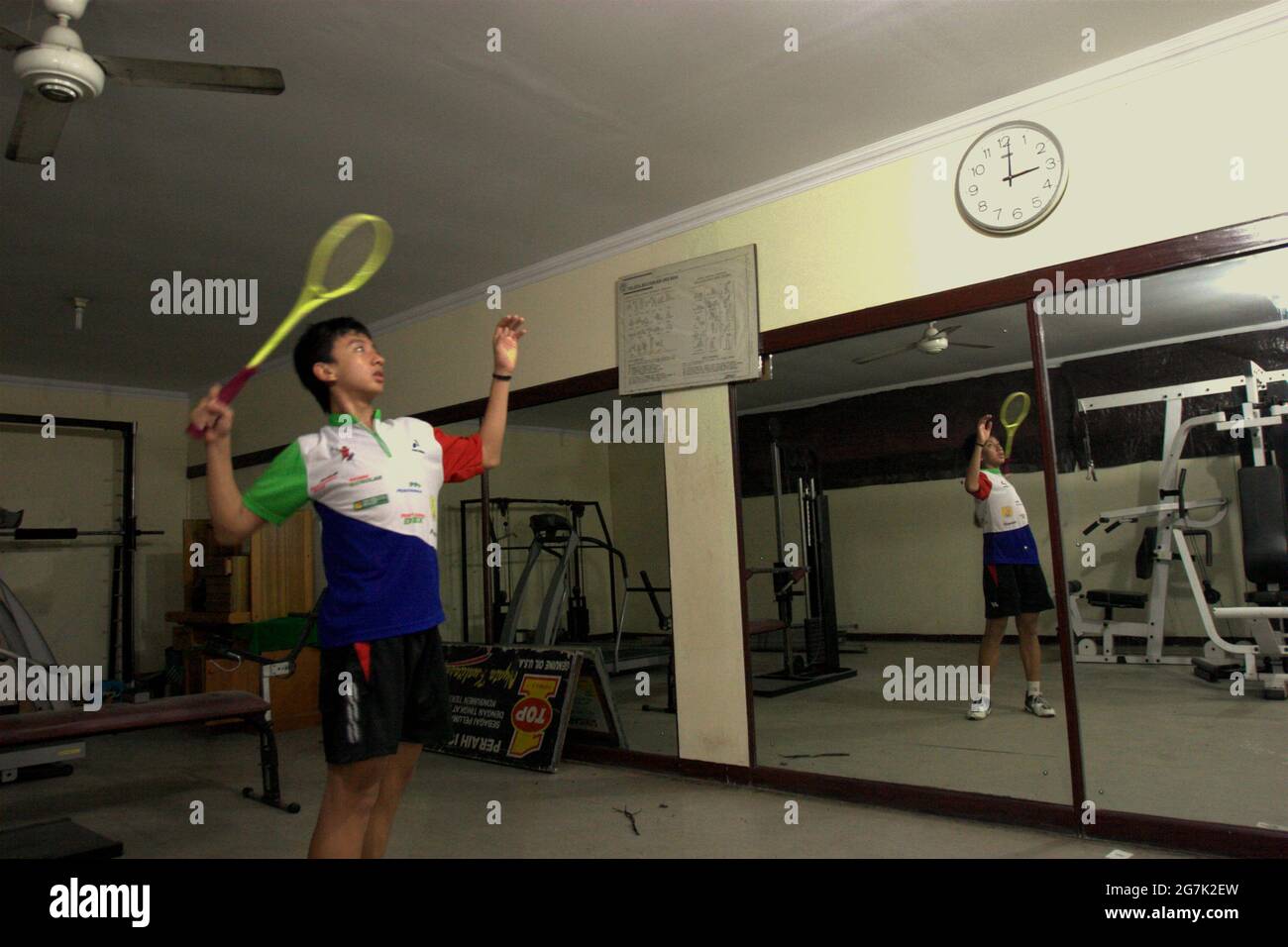 Un giovane atleta di badminton sta praticando vari colpi davanti ad un grande specchio al randello di badminton di Jaya Raya a Jakarta, Indonesia. Foto Stock