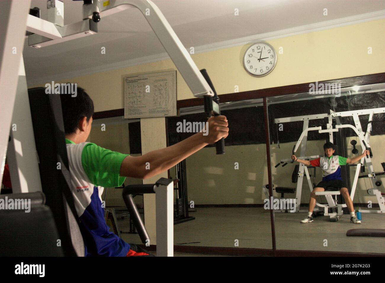 Un giovane atleta di badminton che fa ginnastica di fronte ad un grande specchio al club di badminton Jaya Raya a Giacarta, Indonesia. Foto Stock