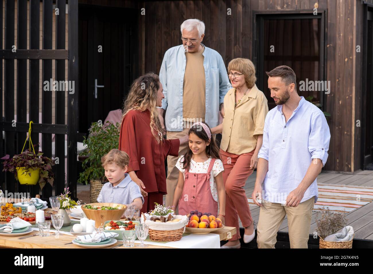 Una grande famiglia si riunisce al tavolo in cortile per mangiare una cena gustosa e festeggiare un'occasione Foto Stock