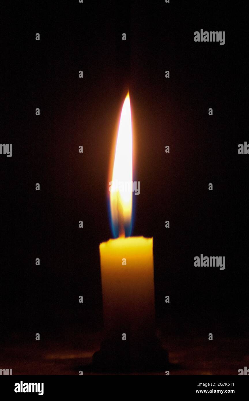 Scatto verticale di una candela calda e morbida che brucia al buio Foto Stock