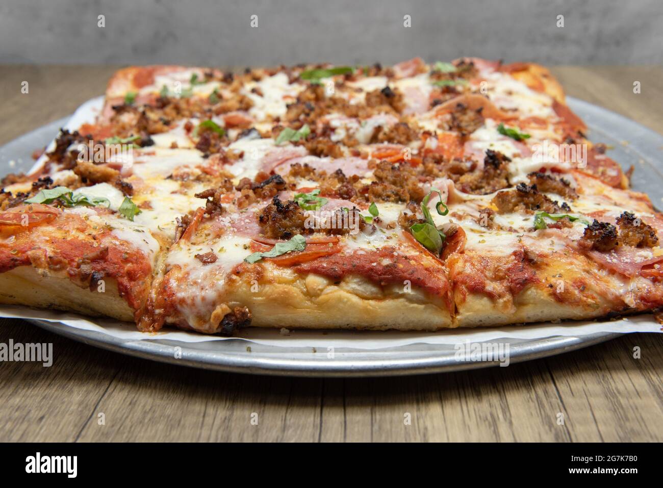 Pizza siciliana tagliata a piazza, ricoperta di deliziosi condimenti e formaggio fuso per questo pasto. Foto Stock