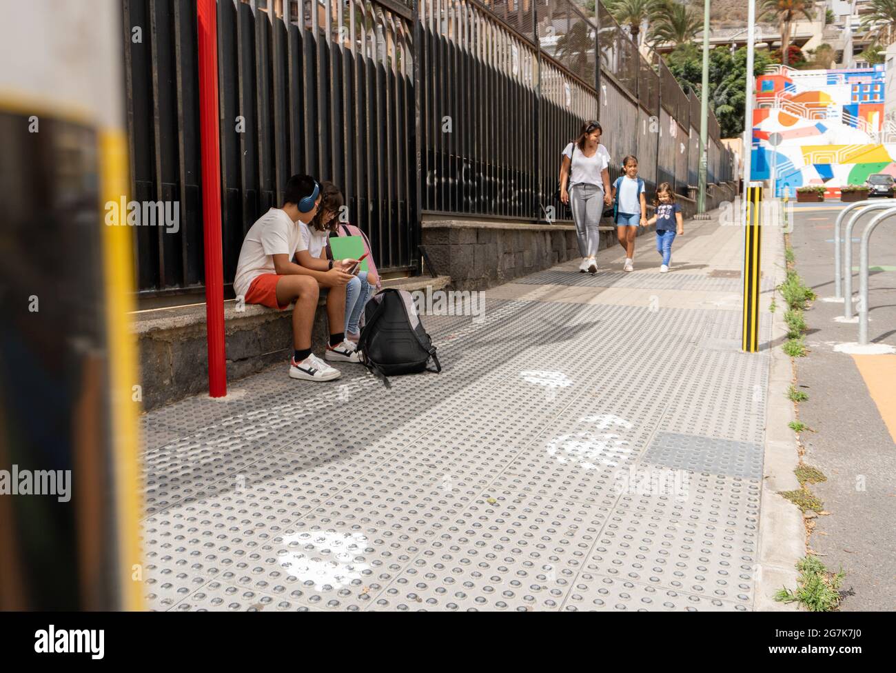 Studenti caucasici in attesa alla fermata del bus scolastico Foto Stock