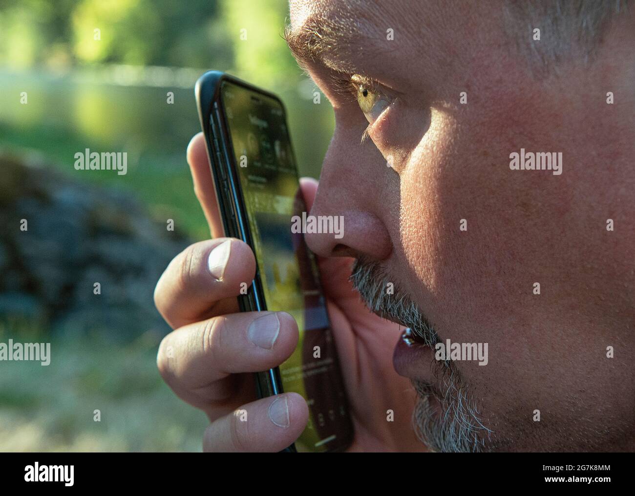 Un uomo che usa la dettatura sul suo iphone. Foto Stock