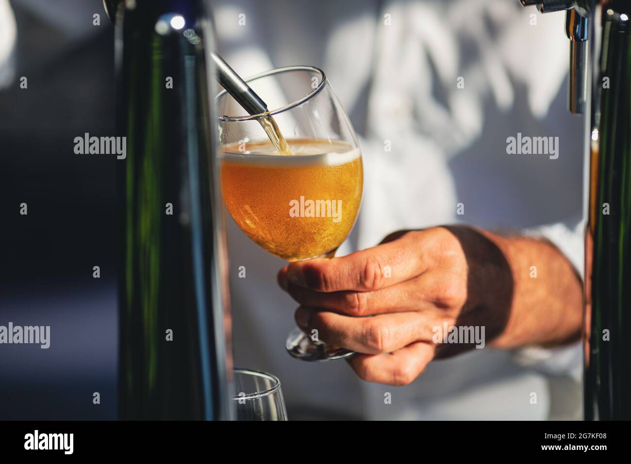Immagine della profondità di campo bassa (messa a fuoco selettiva) con un uomo che versa la birra artigianale da un distributore in un bicchiere. Foto Stock