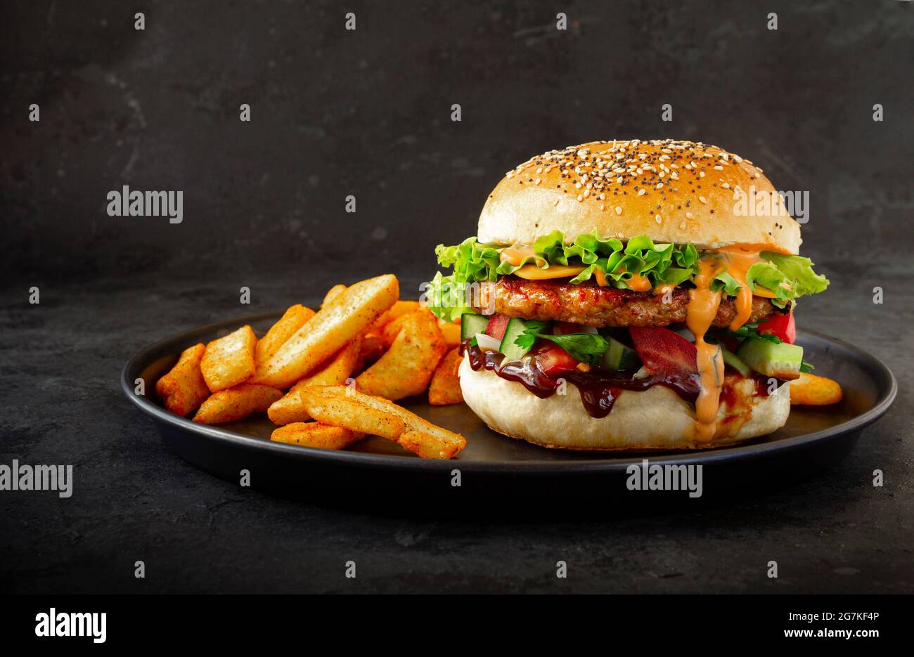 Hamburger di pollo fresco e gustoso con patatine fritte su sfondo scuro Foto Stock