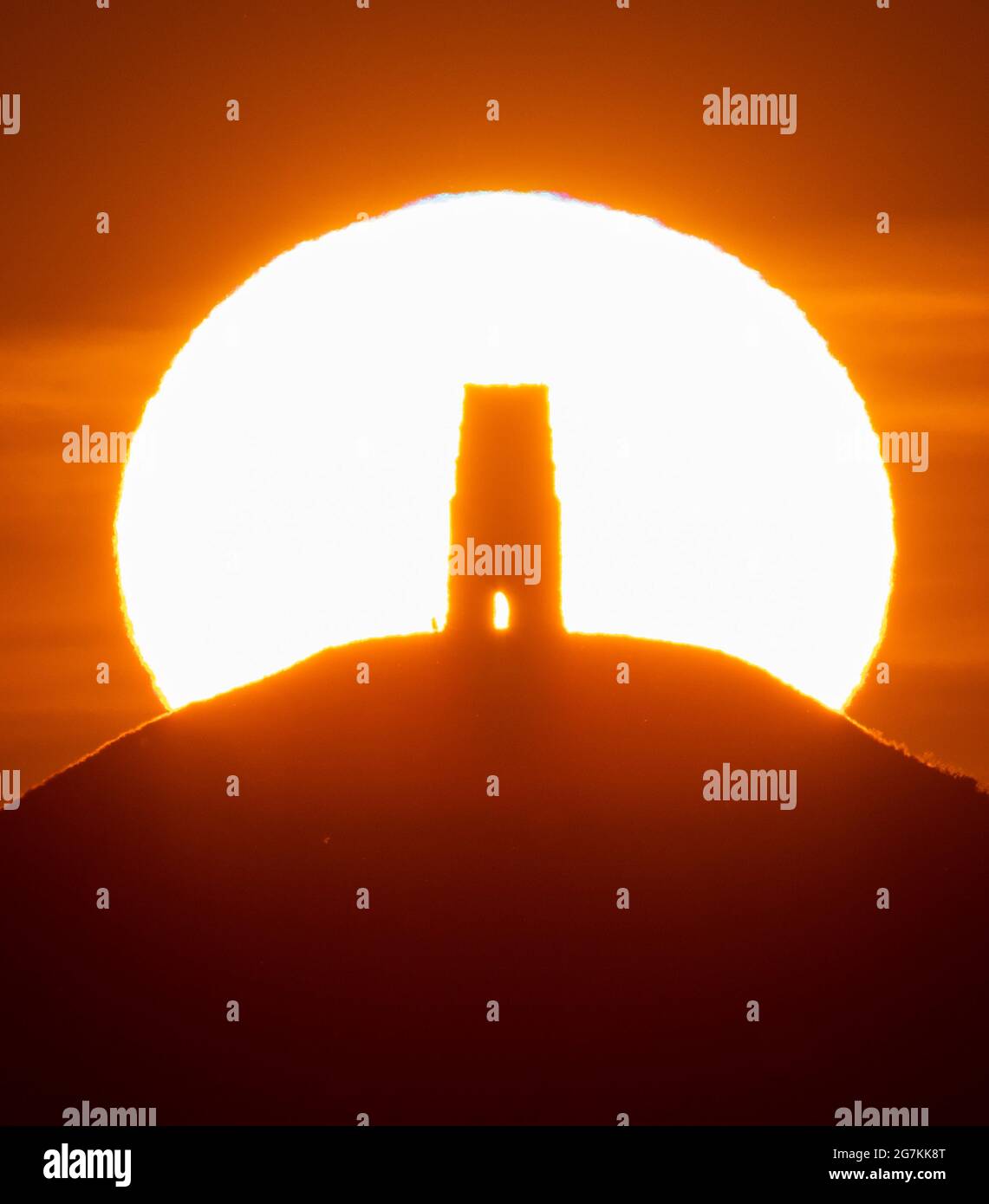 Glastonbury, Somerset, Regno Unito. 15 luglio 2021. Regno Unito Meteo. La torre di San Michele a Glastonbury Tor nel Somerset si staglia contro l'alba in una calda e limpida mattinata estiva all'inizio di un'onda di calore. Picture Credit: Graham Hunt/Alamy Live News Foto Stock