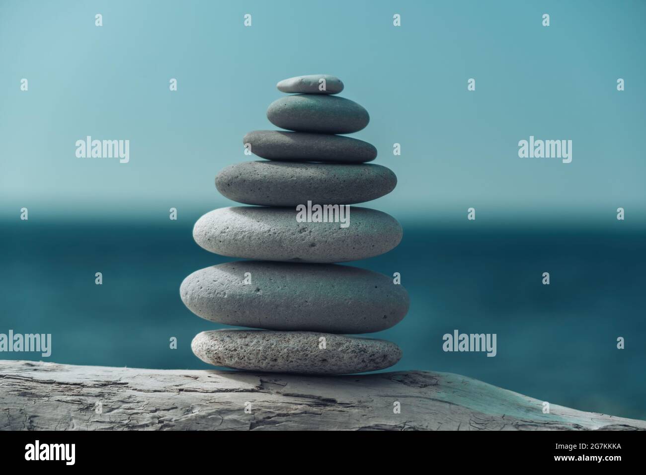 Equilibrata piramide di ciottoli sulla spiaggia in una giornata di sole. Abstract Sea bokeh sullo sfondo. Messa a fuoco selettiva. Pietre Zen sulla spiaggia di mare, meditazione Foto Stock