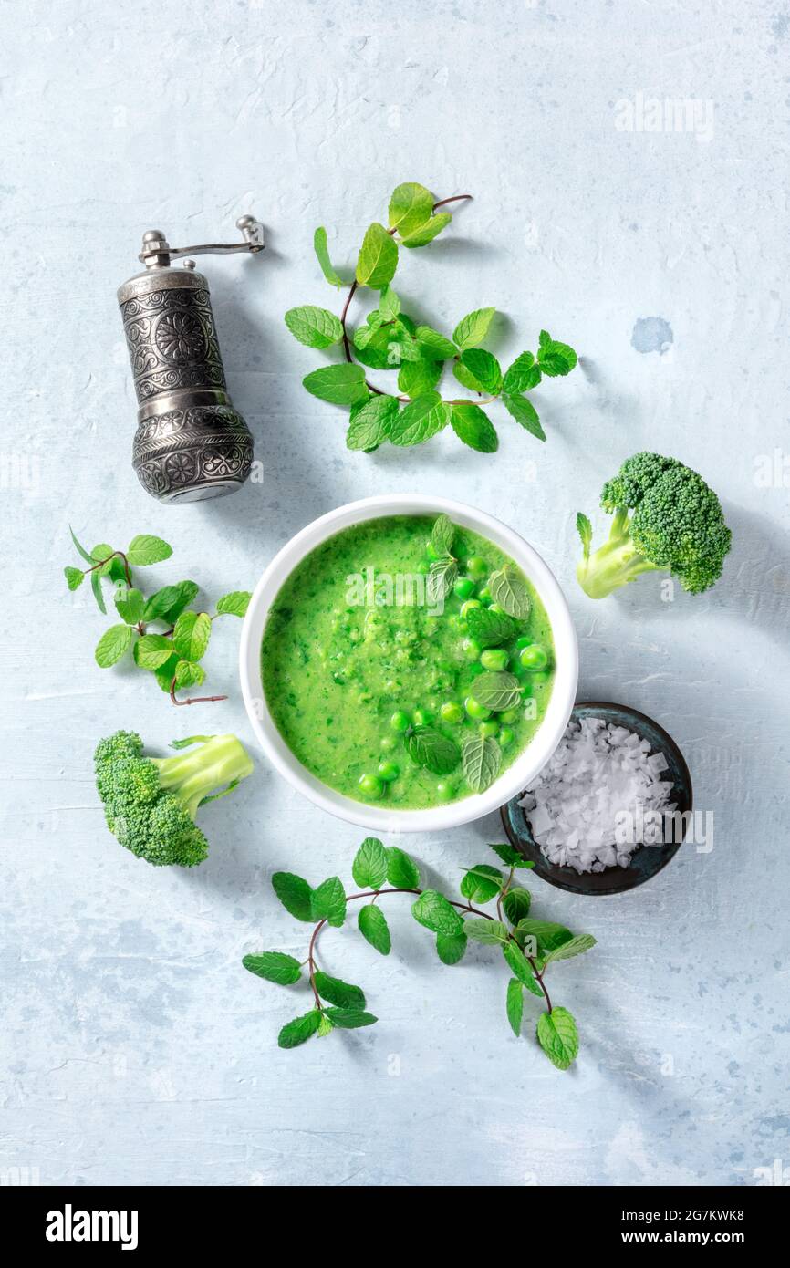 Zuppa verde vegana con ingredienti, colpo di posa piatto. Broccoli, piselli verdi, menta, sale e pepe, sana cucina biologica, dieta a base di piante Foto Stock