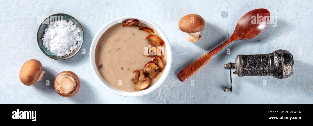 Ingredienti per zuppa di funghi in cucina, vista piana. Funghi cremini con sale e pepe Foto Stock