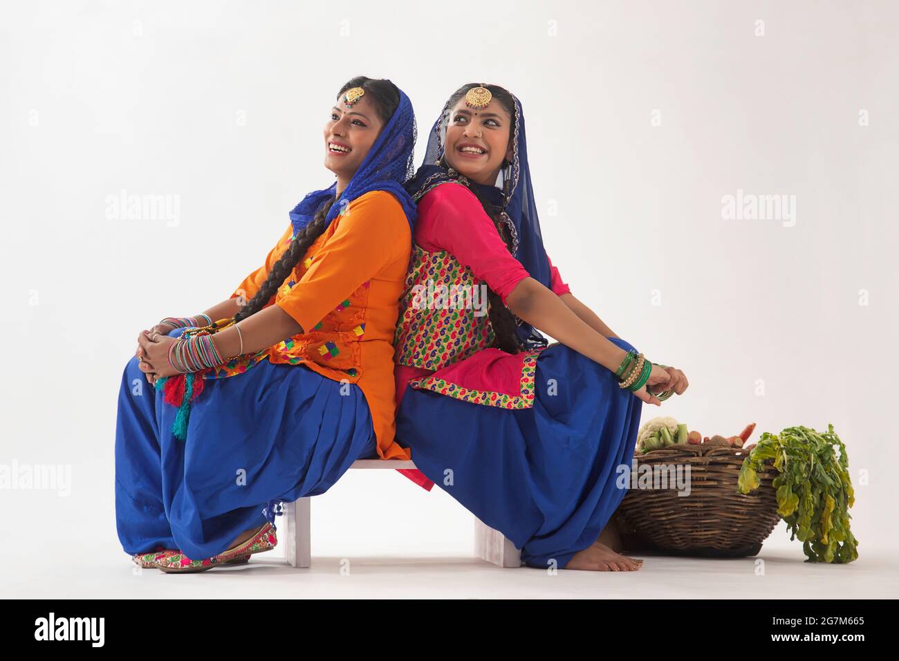 Due ballerini Giddha seduti insieme a un cesto di verdure dietro. Foto Stock
