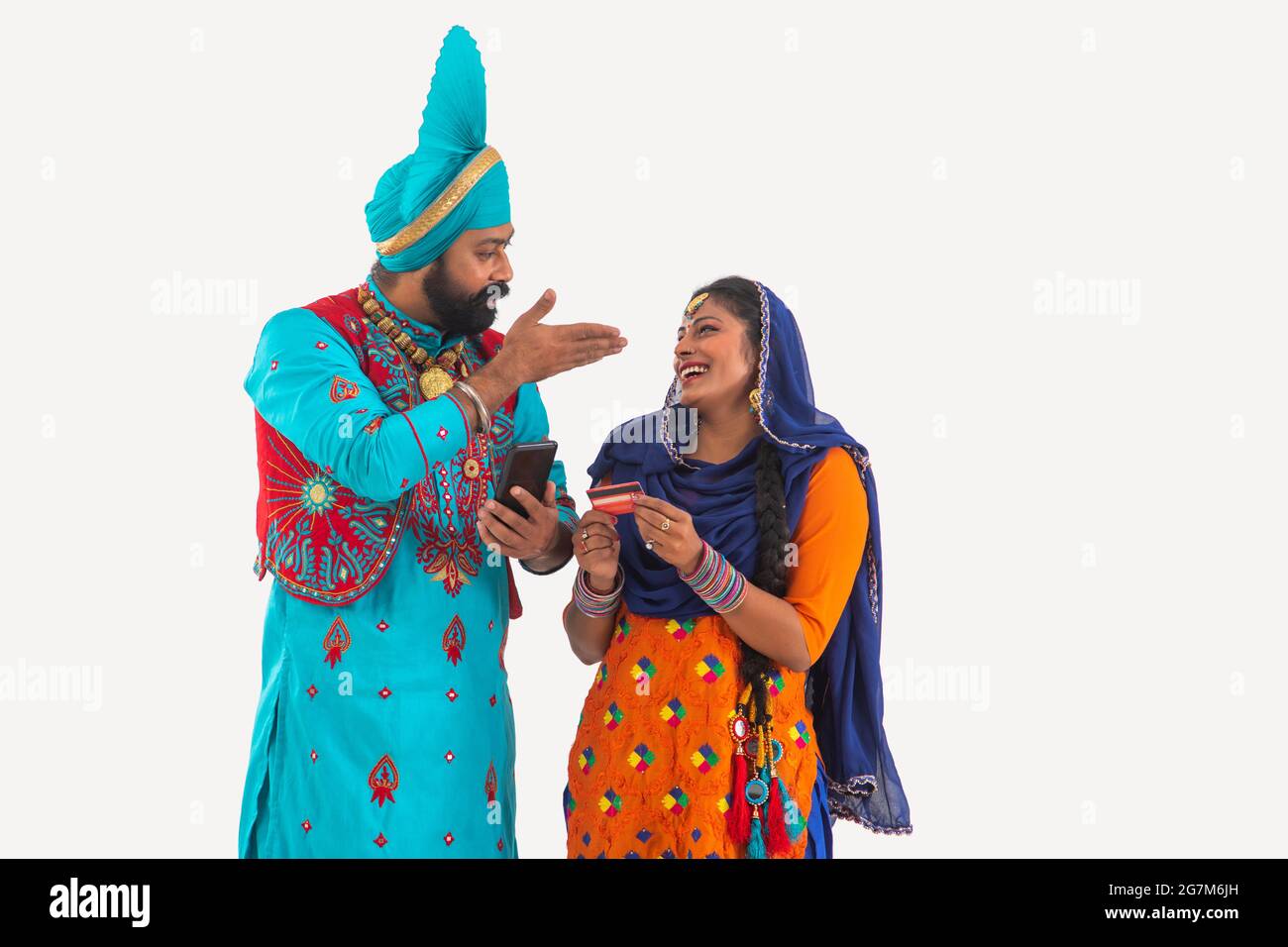 Un Bhangra e UN ballerino di Giddha che discutono giocosamente dei biils che hanno una carta di credito e del mobile in mano. Foto Stock
